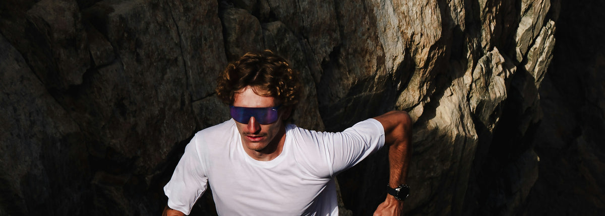 Hombre corriendo en roca con lentes Julbo REACTIV